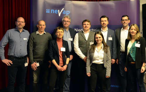 Gruppe von Personen vor violetter Stellwand