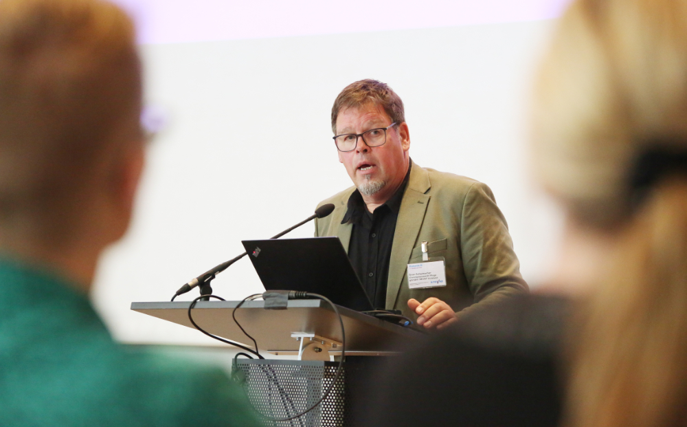 Person am Mikrofon spricht vor Zuschauenden